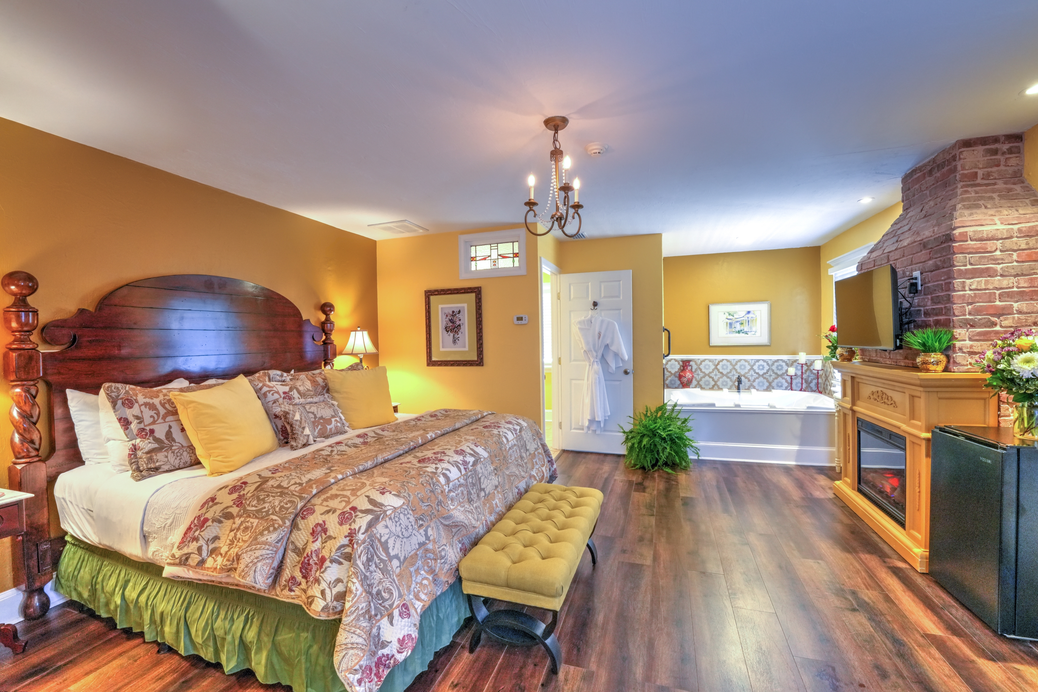 Spacious and elegant bedroom with king bed, upholstered bed bench at foot of the bed and in the far corner a whirlpool tub.