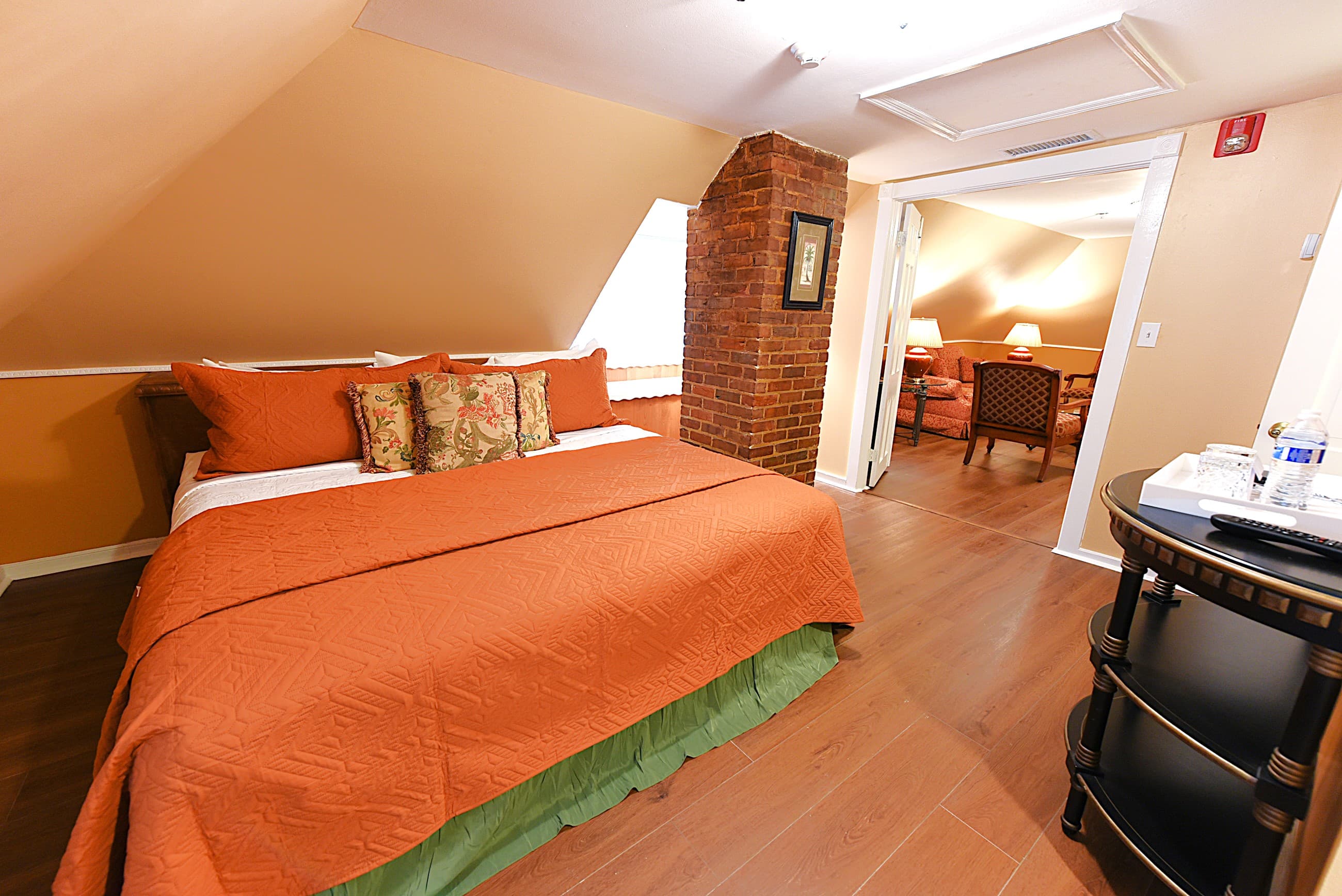 Cozy third-floor bedroom opposite the king bed is a bureau with a flat-screen TV.  To the left of the TV is the bathroom doorway, and recessed in a nook to the right is a whirlpool tub for two.