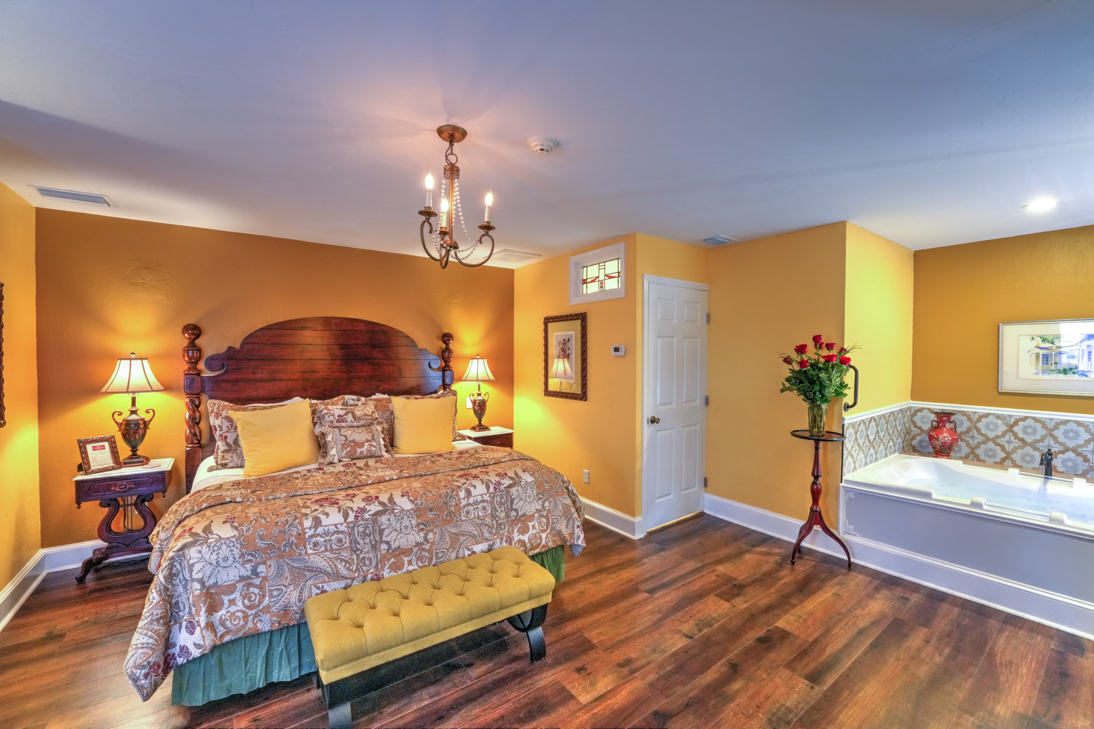 The sitting area at the foot of the bed features upholstered bed bench and two matching nighlamps