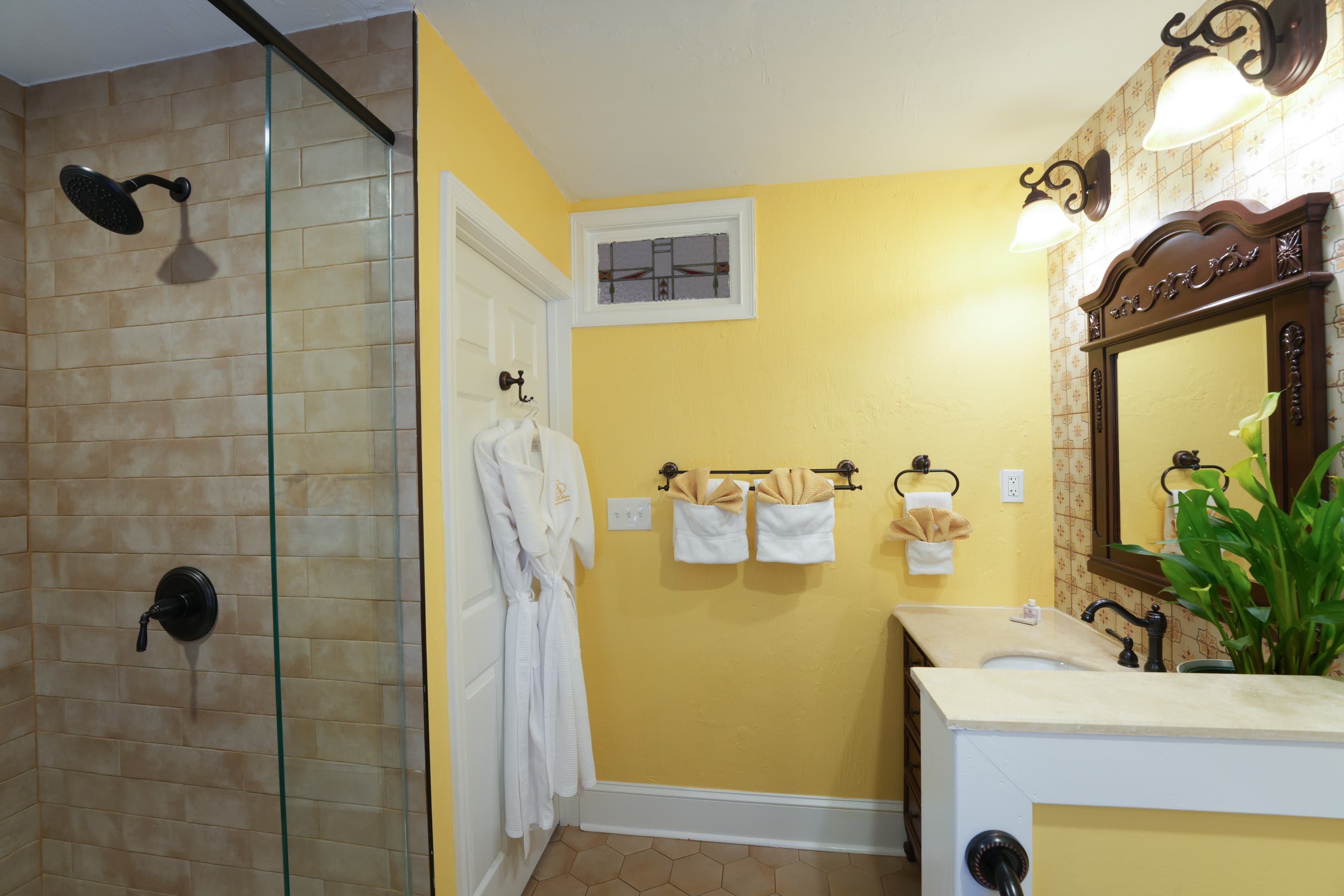 Private bathroom with tiled shower, sink with vanity, and toilet.