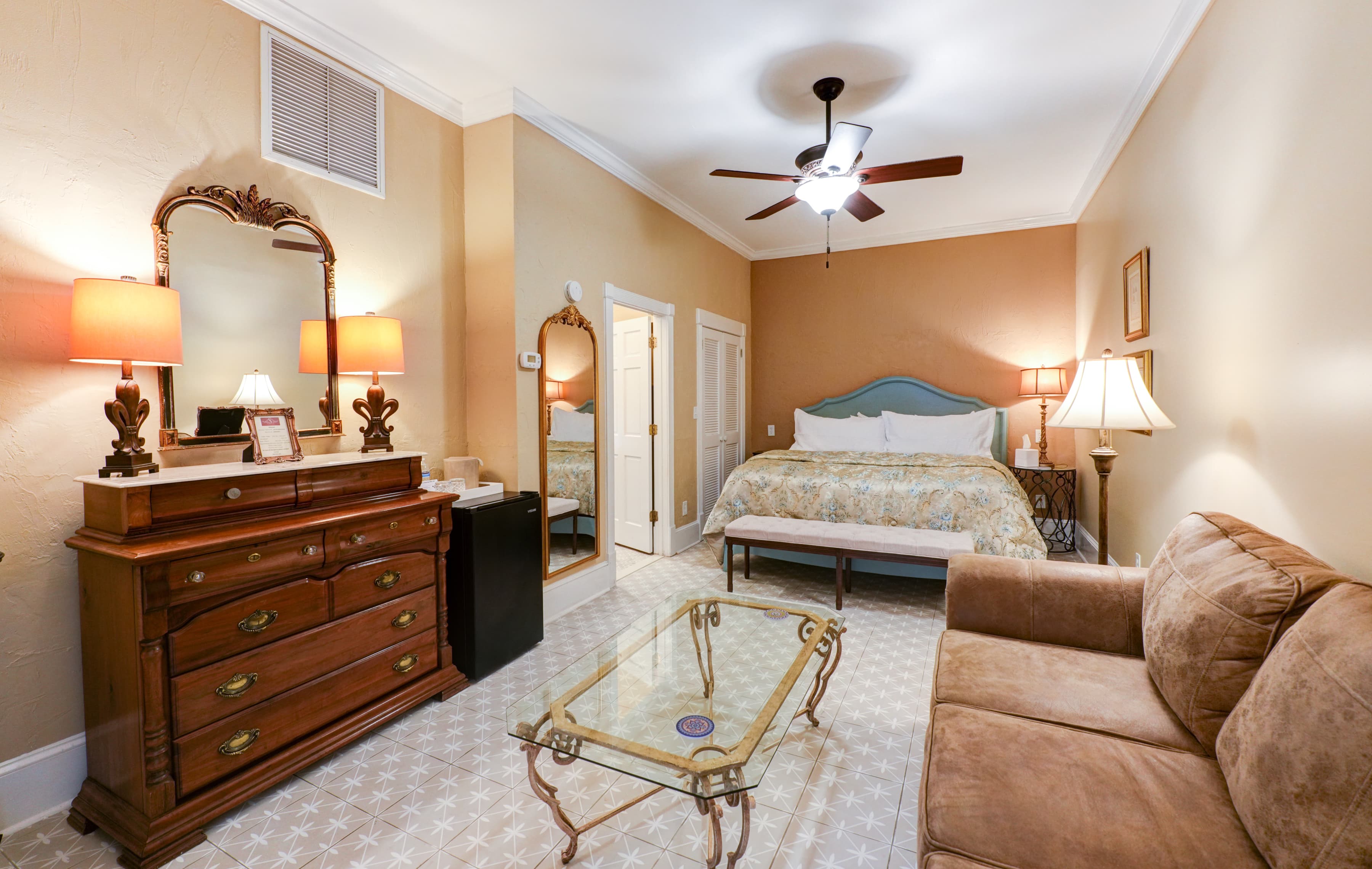 Welcoming guestroom with king bed and a sitting area with sofa and coffee table.