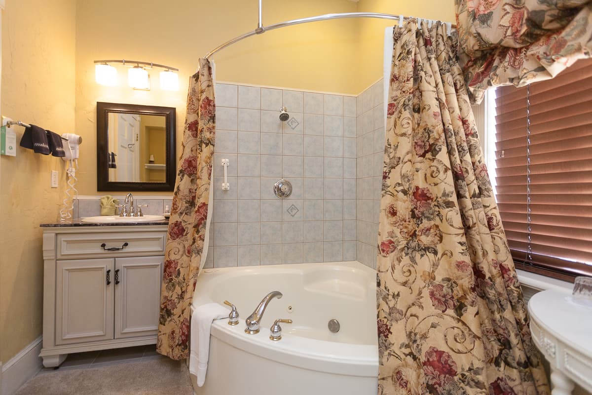 Bathroom with tiled corner whirlpool tub and shower combination and sink with vanity.