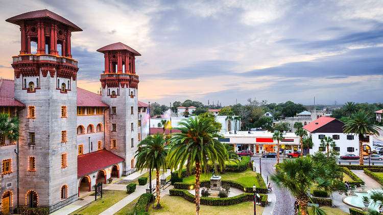 Historic building with towers surrounded by palm trees and a dusky sky.