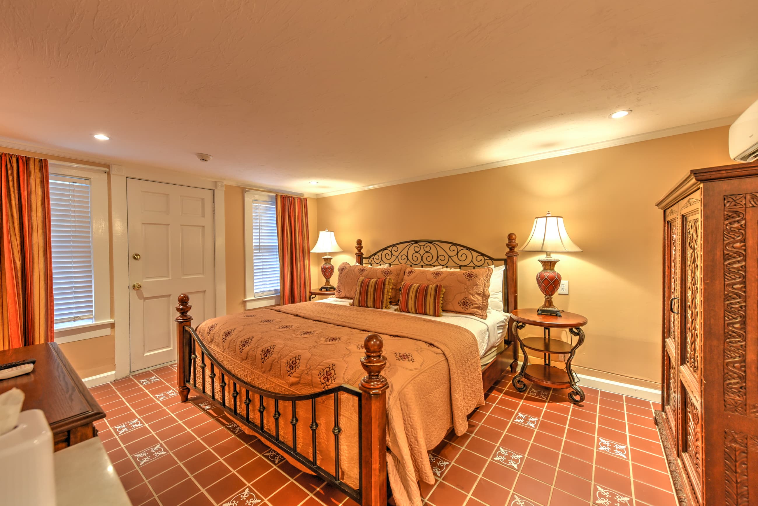 A cozy bedroom featuring a decorative bed, two lamps, and traditional furnishings.