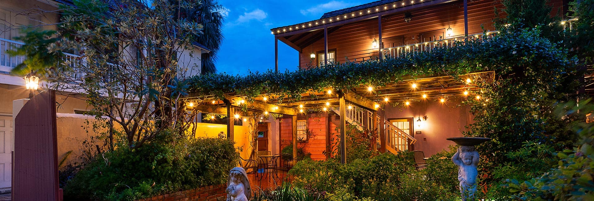 A beautifully lit garden area with a wooden pergola and cozy seating under a twilight sky.