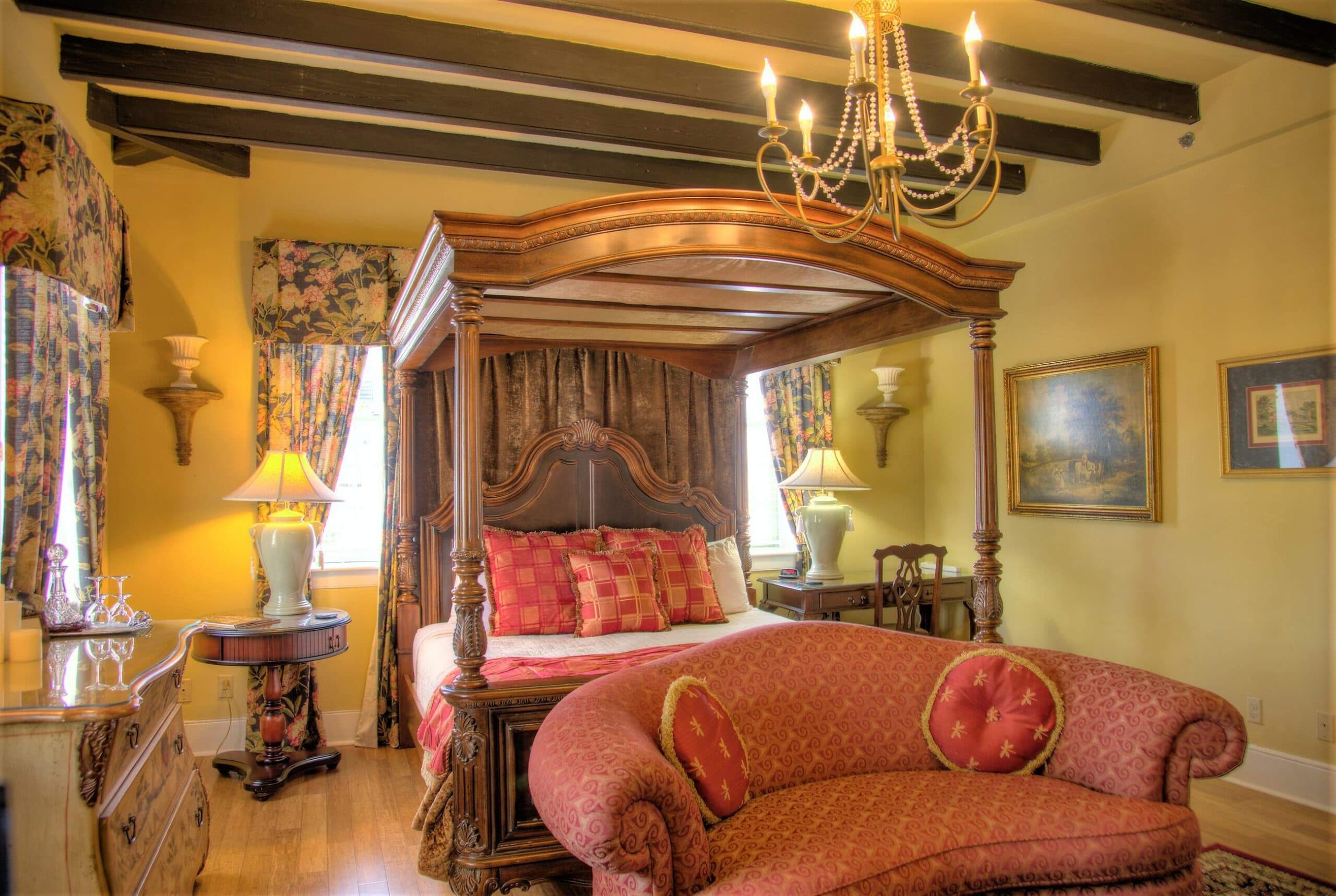 A luxurious bedroom featuring a four-poster bed, a vintage couch, and elegant lighting.