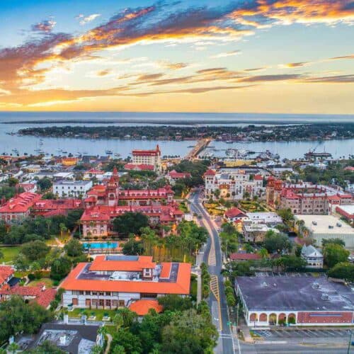 Aerial view of a coastal city at sunset, featuring colorful buildings and a harbor. Aerial view of a coastal city at sunset, featuring colorful buildings and a harbor.