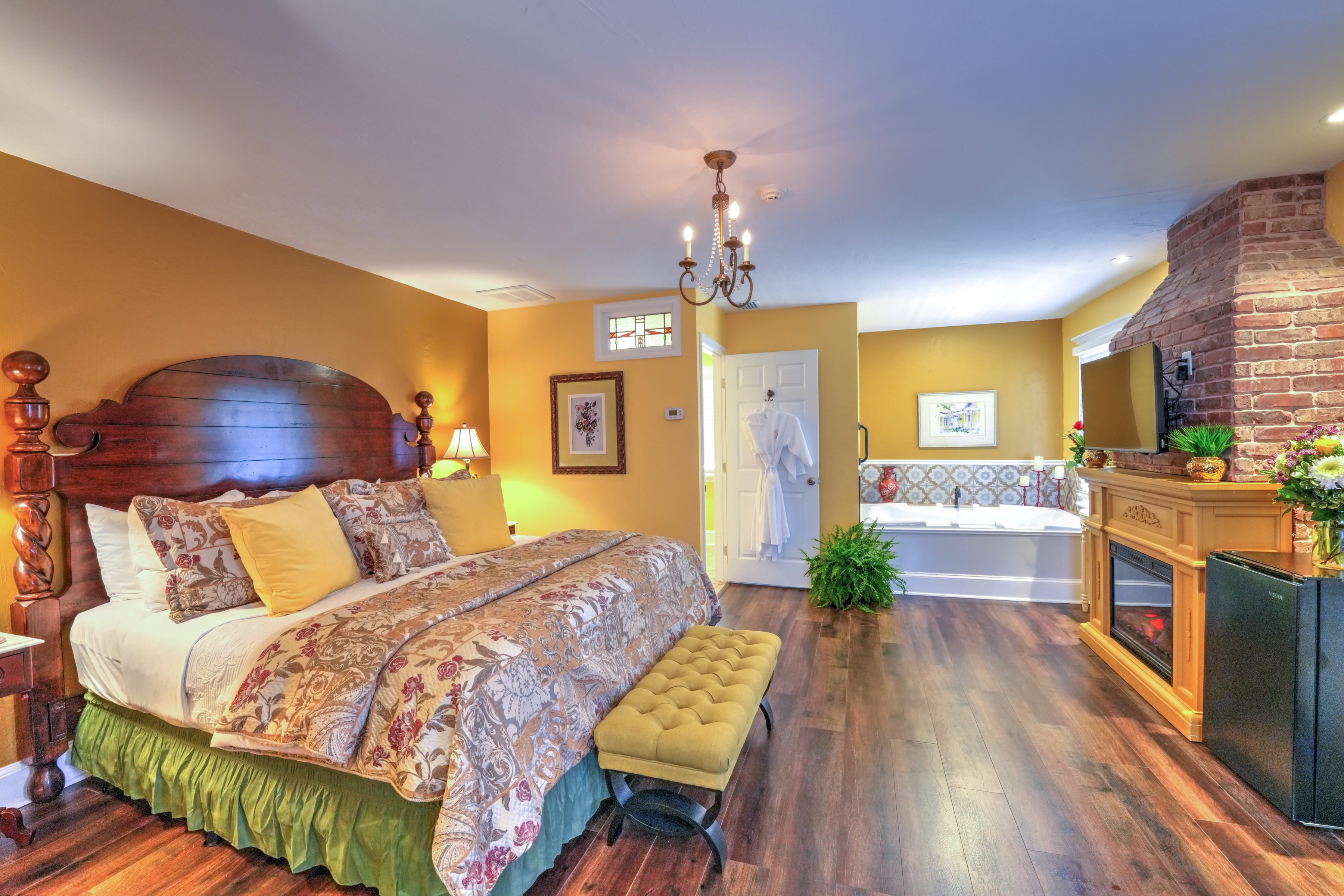 Spacious and elegant bedroom with king bed, upholstered bed bench at foot of the bed and in the far corner a whirlpool tub.