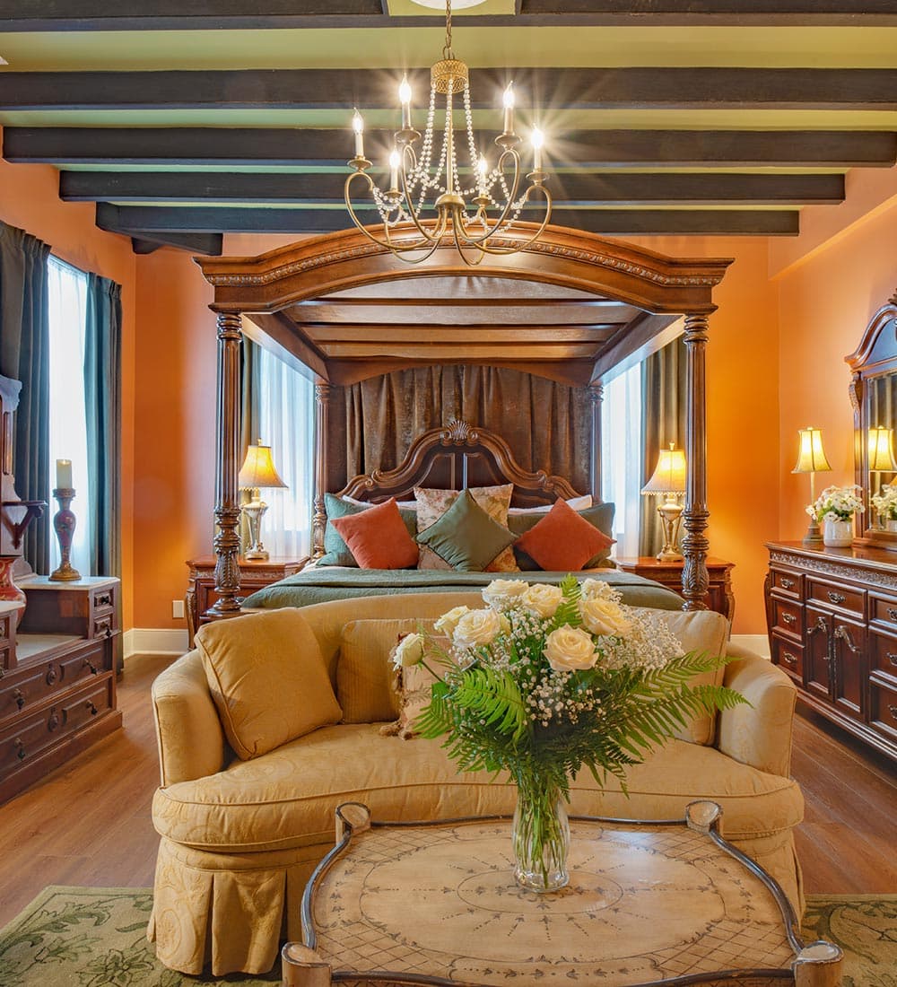 A beautifully decorated bedroom featuring a four-poster bed, plush seating, and elegant decor.