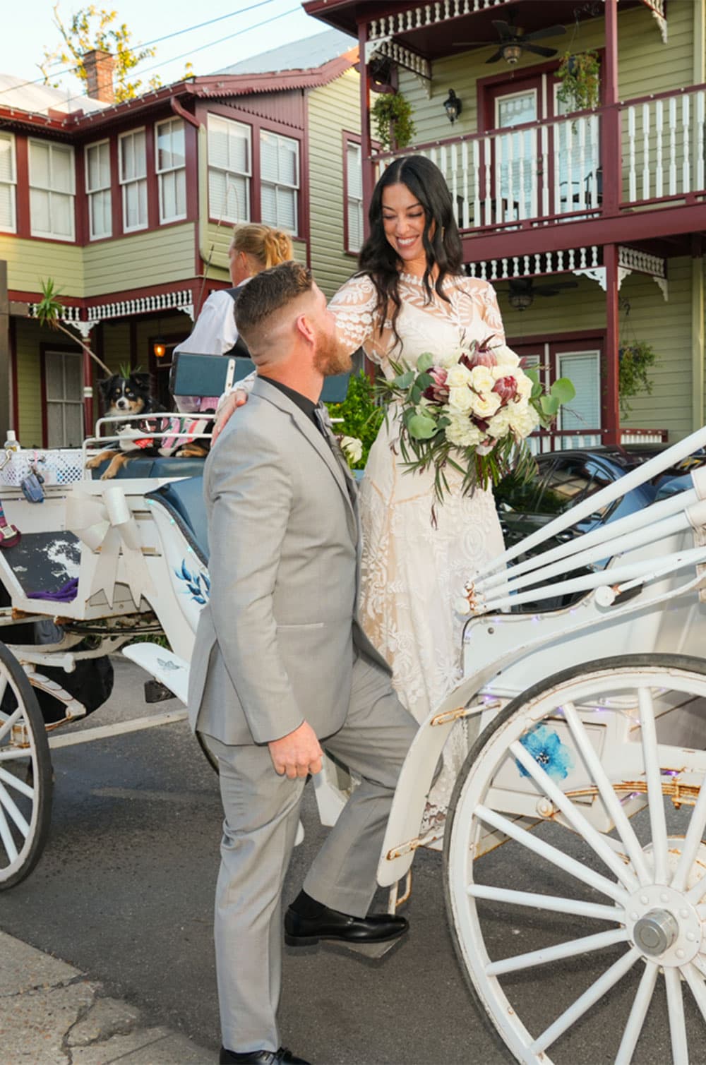 A couple exchanges loving glances while the bride, in a white dress, steps onto a decorated horse-drawn carriage.