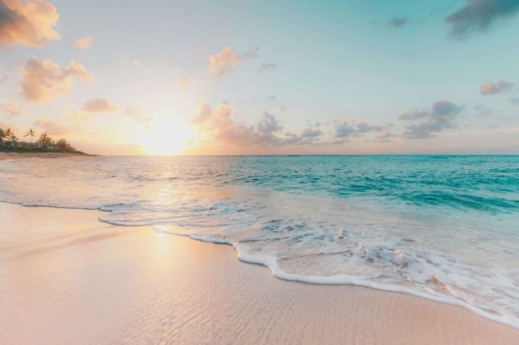 A serene beach scene at sunset with soft waves lapping at the shore.