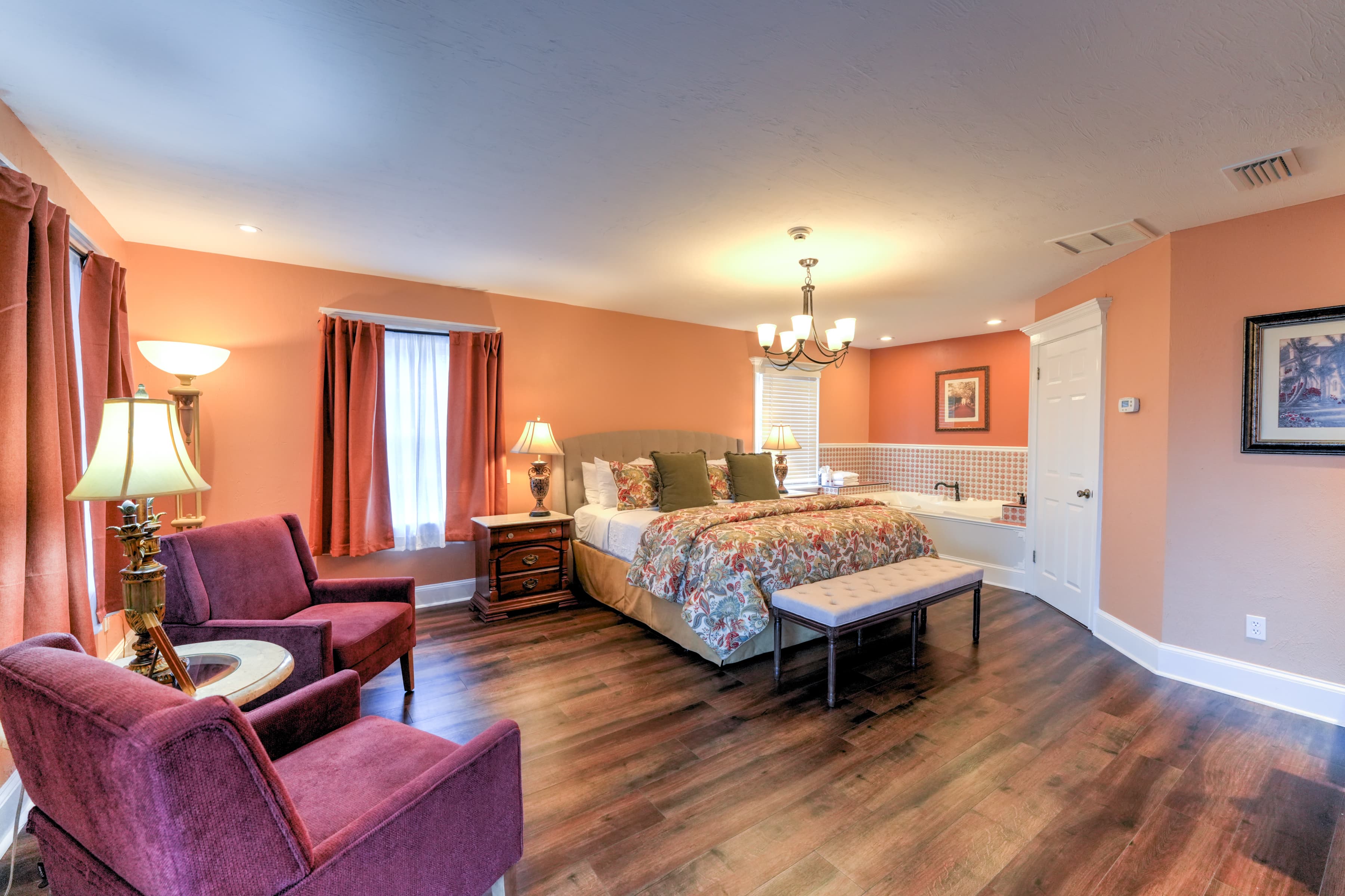Cozy bedroom featuring a large bed, seating area, and warm-colored walls.