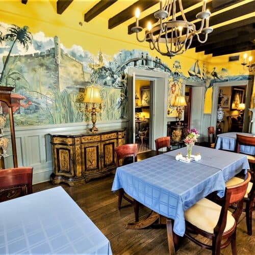 A cozy dining room with blue tables, wooden chairs, and colorful mural walls. A cozy dining room with blue tables, wooden chairs, and colorful mural walls.
