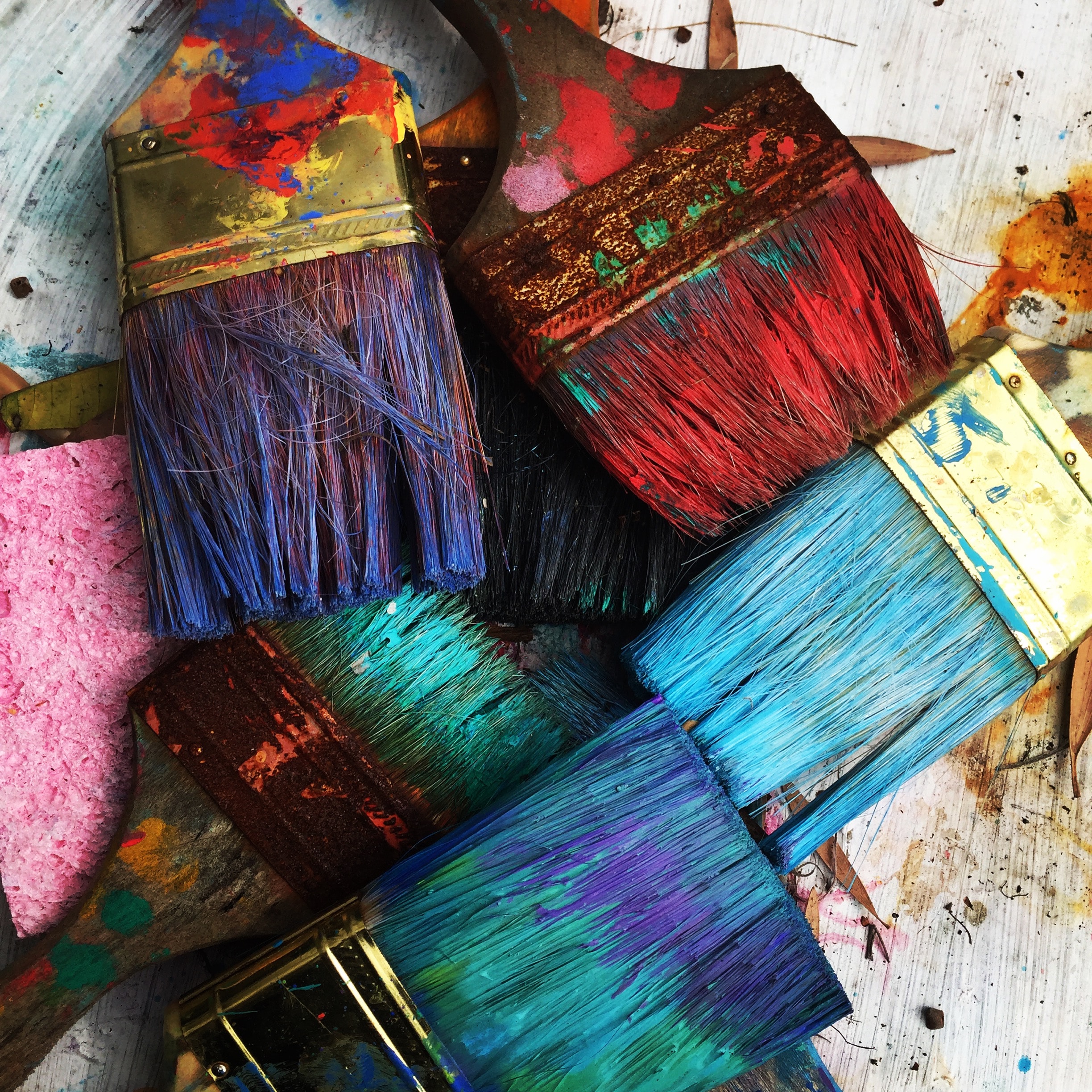 Several colorful paints brushes lay on a white work space.